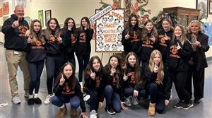 Superintendent Niesz and Dr. Quinn stand with girls wrestling champions holding up sign for number 1